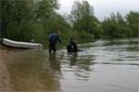picture of owner collecting newfoundland dog which has returned to shore and assisting stranger from water