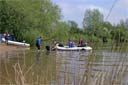 picture of owner collecting black newfoundland dog and boat at shoreline