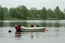 picture of black newfoundland dog towing boat towards shore the water steward in the front of the boat is holding the rope